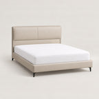 ANJU low profile bed frame with beige padded headboard, shown with a mattress, three-quarter view on plain background