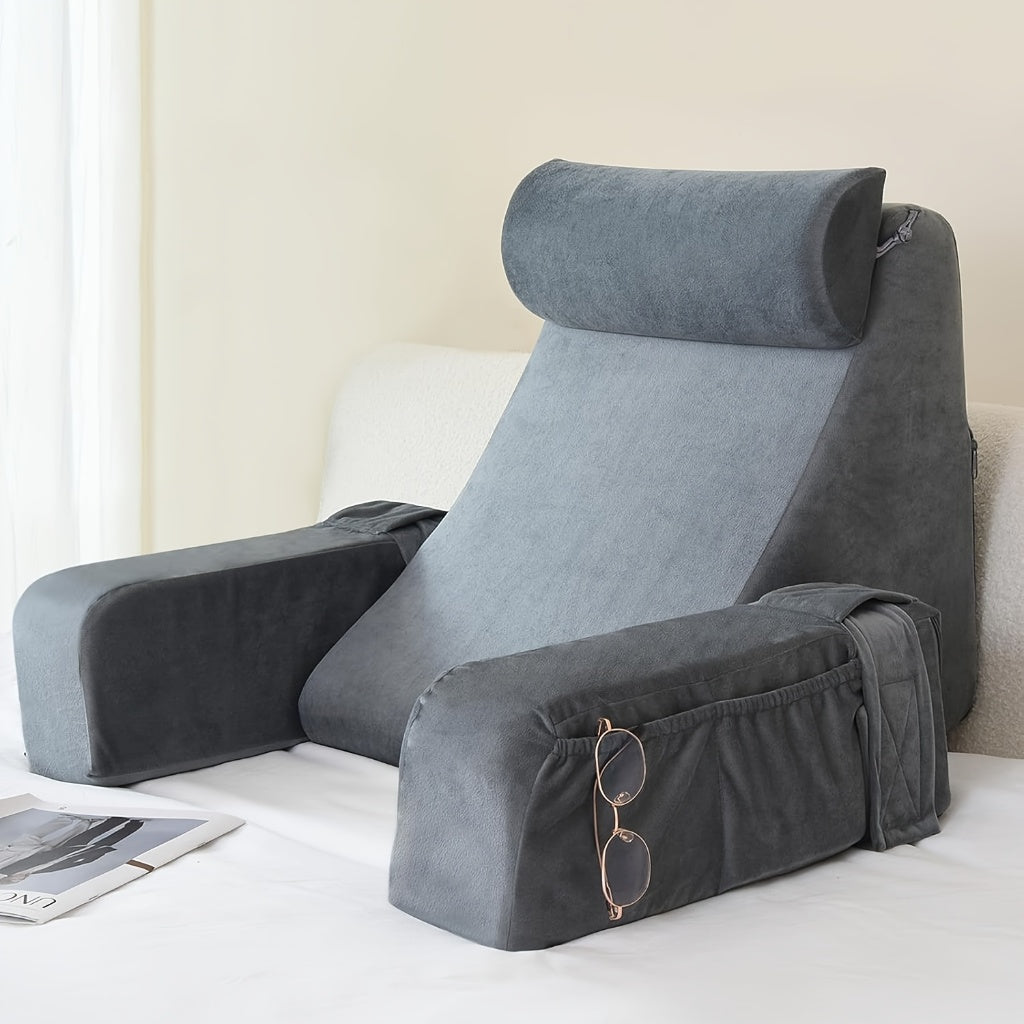 Gray ANJU reading pillow for bed with arms, headrest bolster and side pocket holding glasses, propped on a bed